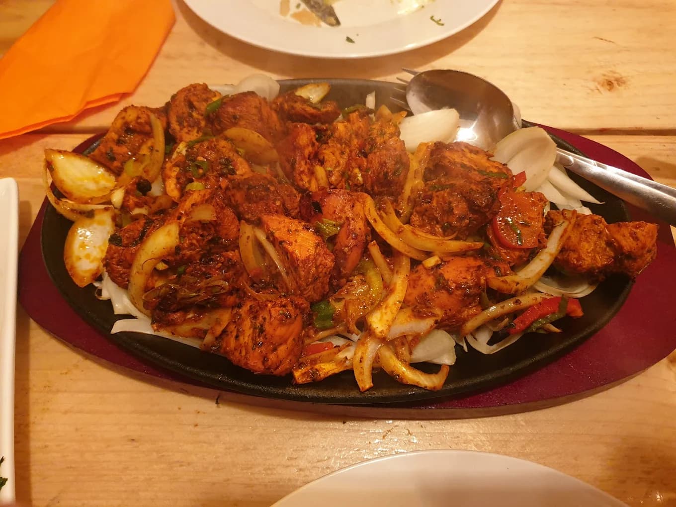Sizzling cast-iron platter of spiced chicken chunks with sautéed onions and peppers.